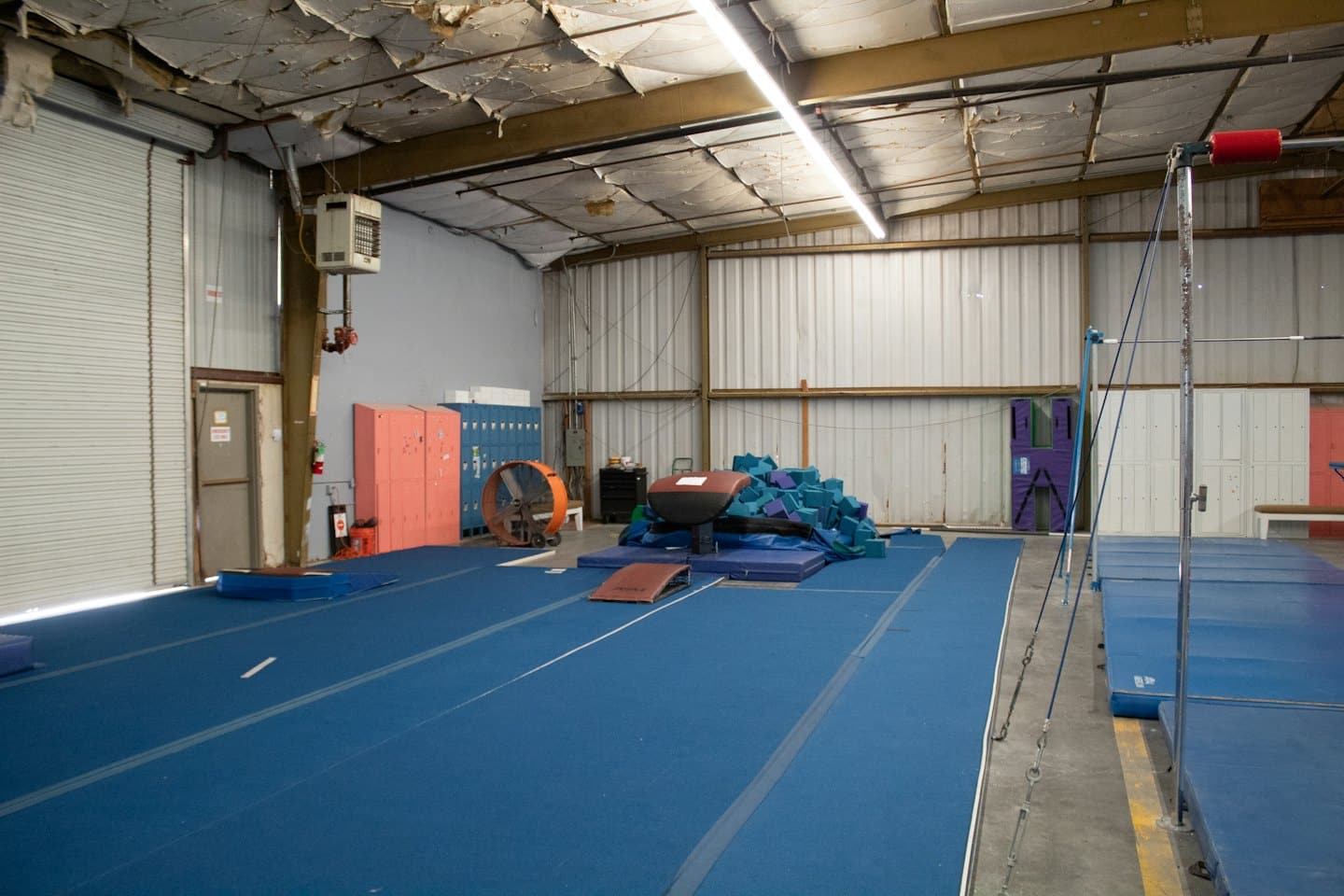 Palestra di ginnastica vuota con pavimenti imbottiti blu e attrezzature.