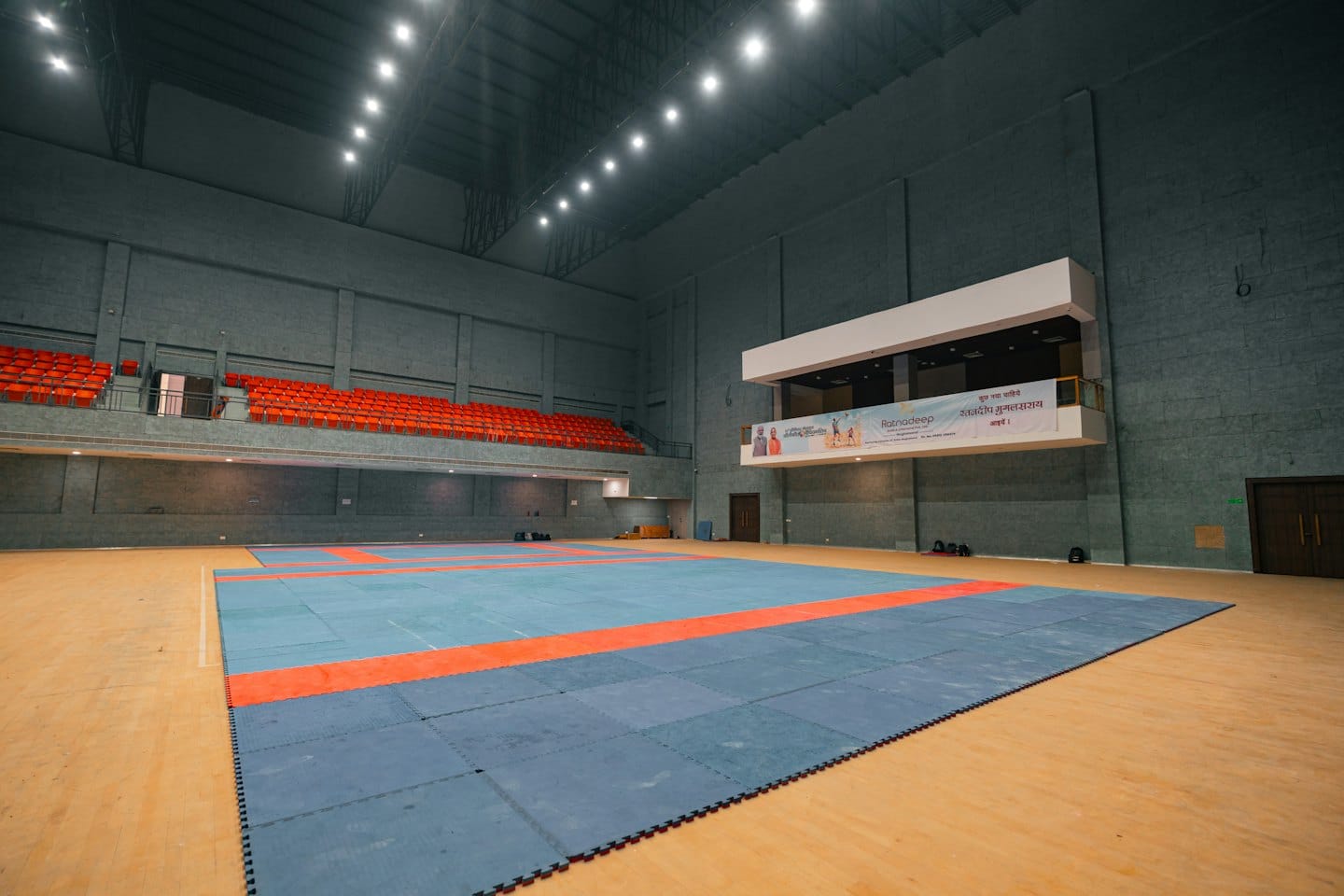 Arena sportiva vuota con tappetino da kabaddi su pavimento in legno.