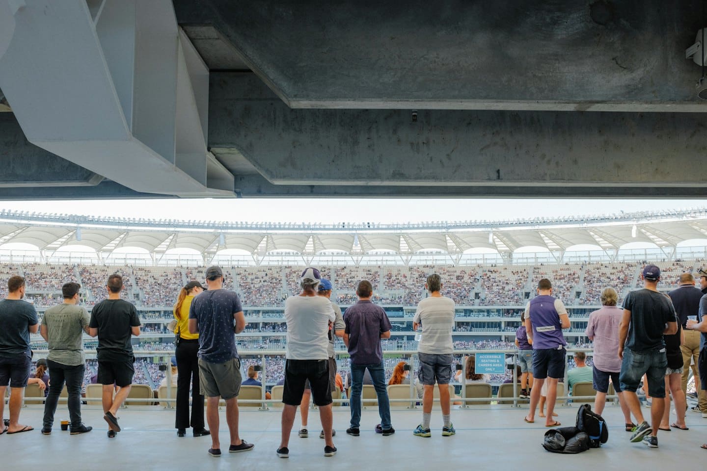 Spettatori guardano una partita sportiva dal corridoio di uno stadio.
