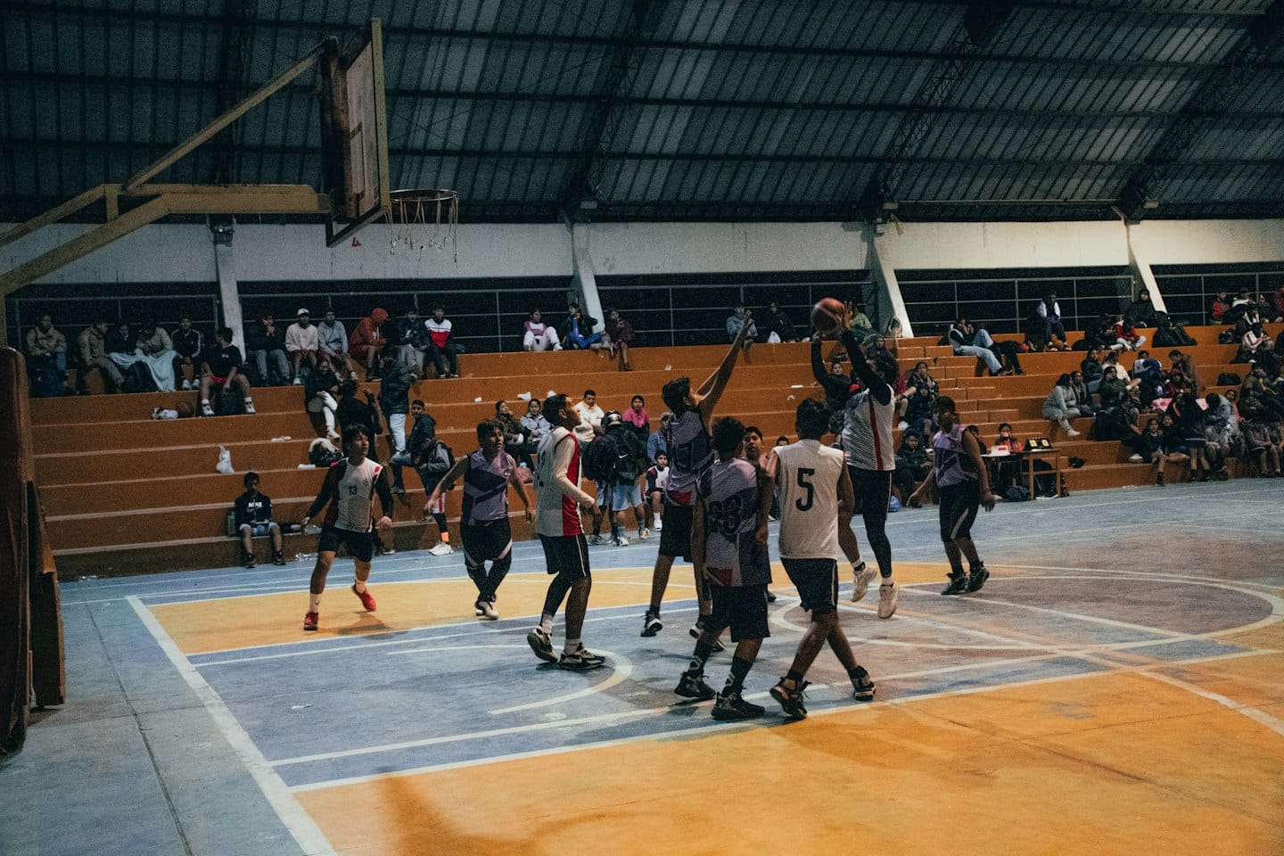Uomini giocano una partita di pallacanestro indoor veloce su un campo.
