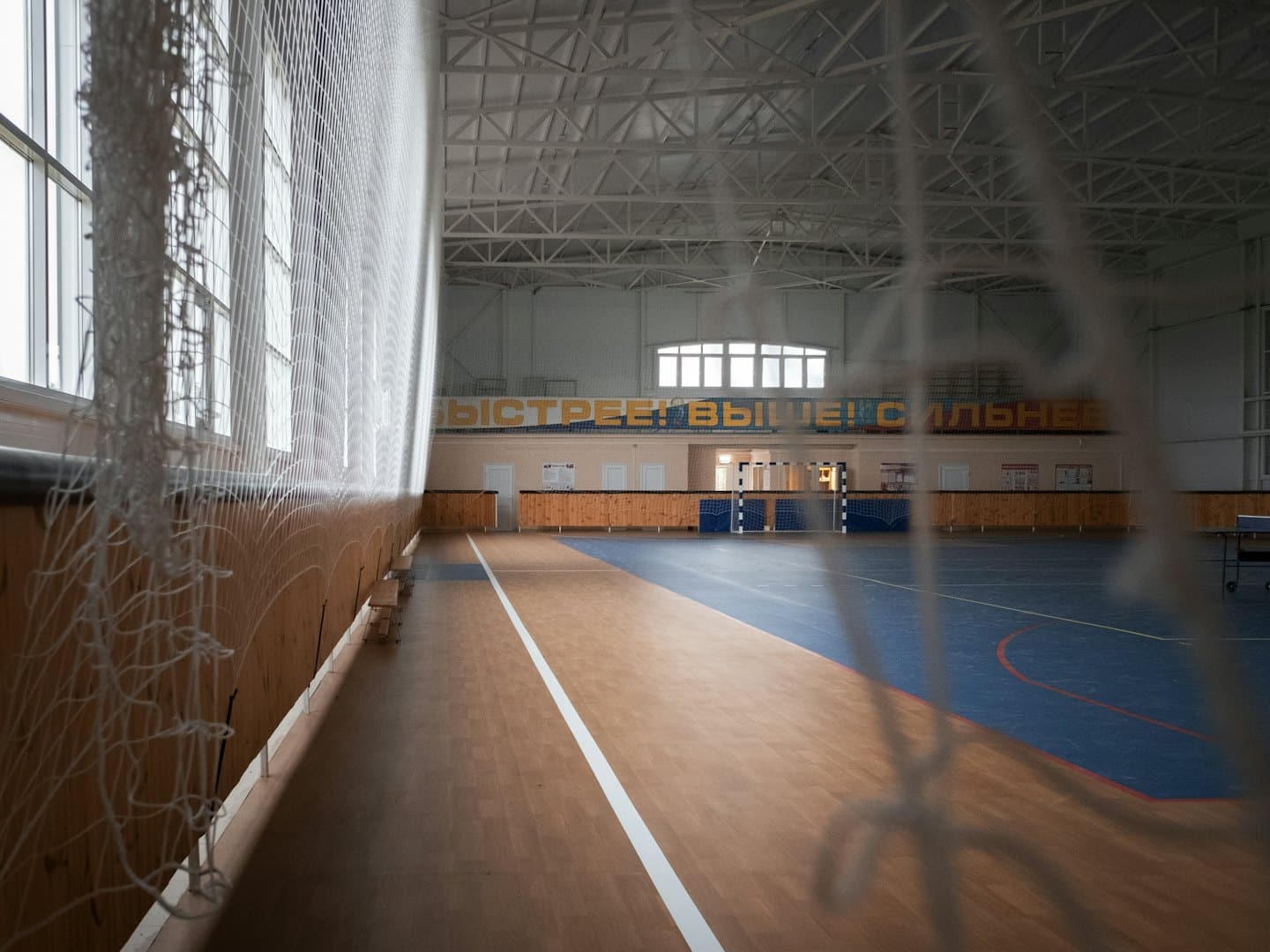 Palazzetto dello sport vuoto con campo blu e rete bianca.