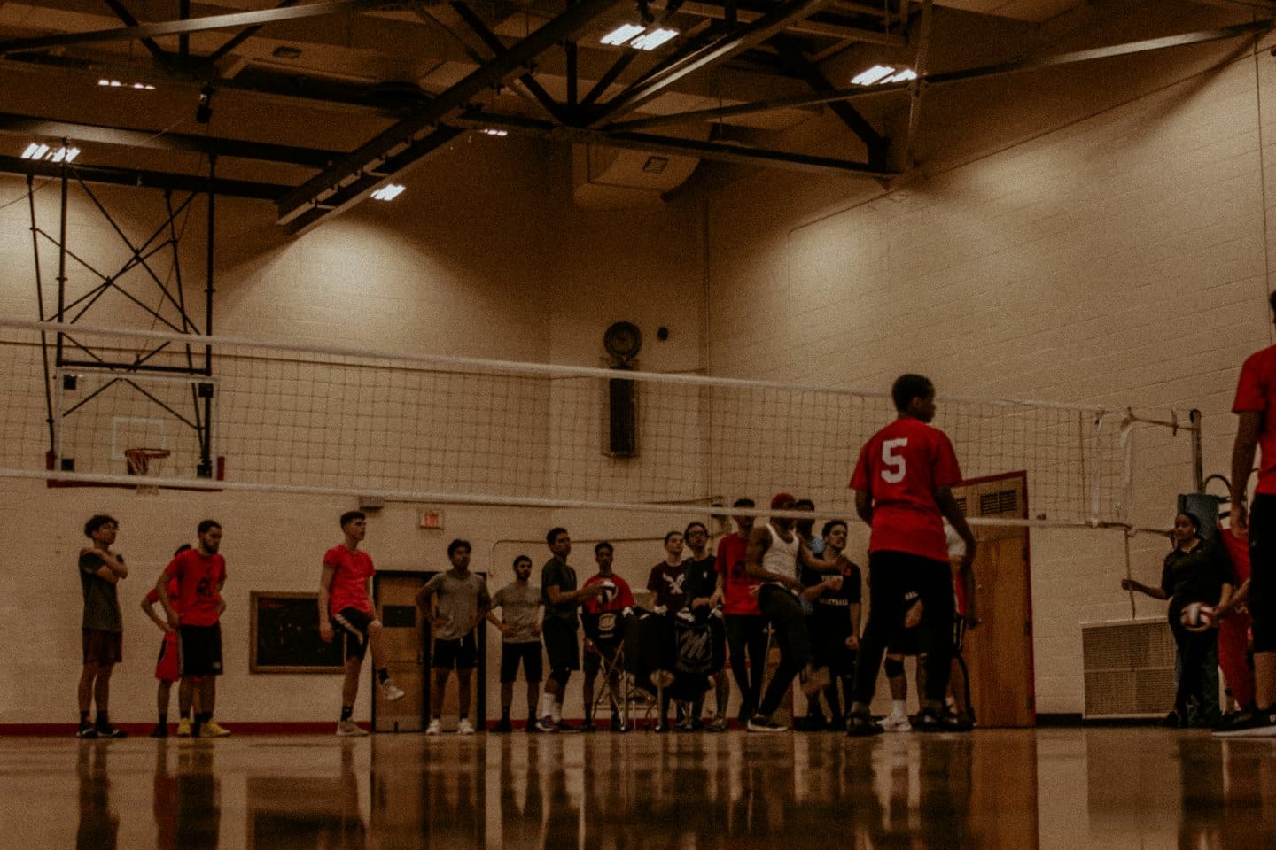 Giovani adulti giocano a pallavolo in palestra.