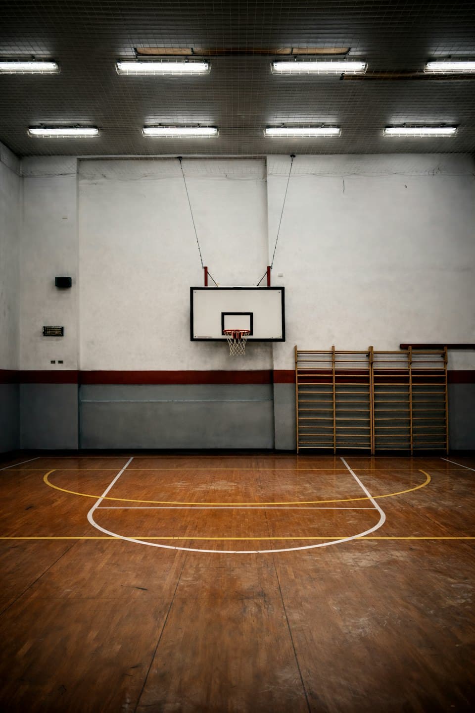 Campo da basket vuoto con pavimenti in parquet lucido e spalliere.
