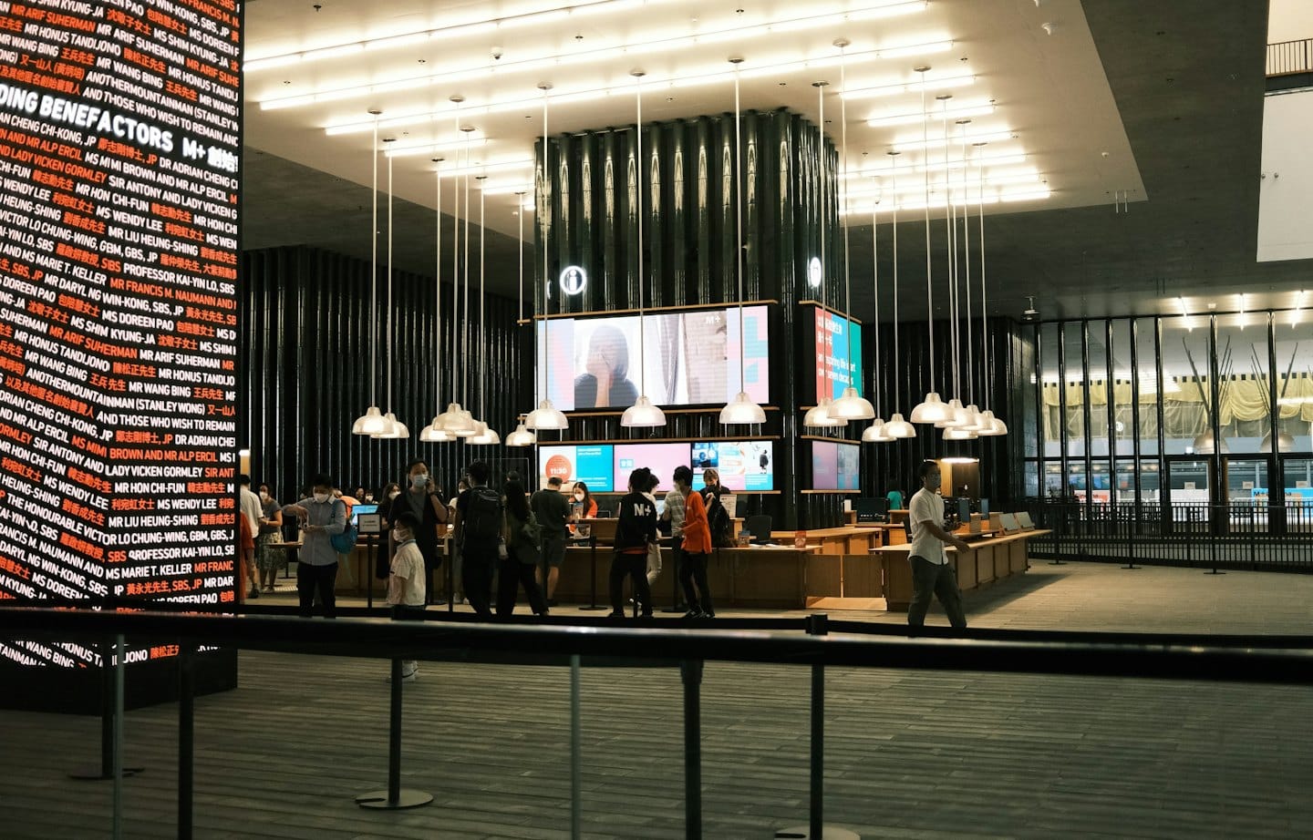 Persone interagiscono a una reception moderna con display digitali.